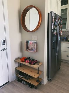 a kitchen with a refrigerator, shoe rack and mirror on the wall next to it