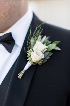 a man in a tuxedo wearing a boutonniere with white flowers