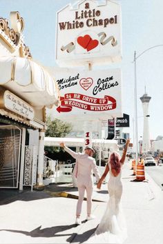 a man and woman are walking down the street in front of a white chapel sign