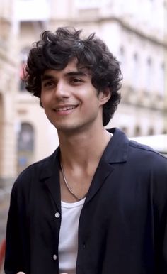 a young man with curly hair smiling at the camera