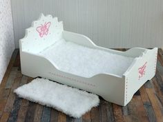 a white doll bed sitting on top of a wooden floor