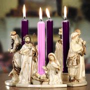 three lit candles with figurines in front of them