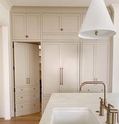 a white kitchen with an island sink and large cupboards in the back ground area