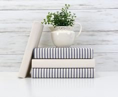 three books stacked on top of each other next to a plant in a white vase