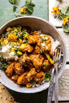 a bowl filled with chicken and rice next to a fork on top of a table