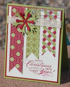 a close up of a christmas card on a sand surface with rocks in the background