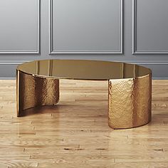 a gold coffee table on a wooden floor