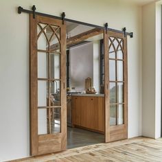 an open sliding door in a room with wood floors and white walls, leading to a kitchen