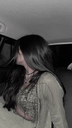 a woman sitting in the back seat of a car next to a man with long hair