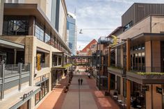 an empty city street lined with buildings and people walking on the sidewalk in front of them