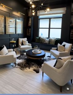 a living room filled with lots of white furniture and black wall art on the walls