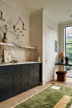 a kitchen with marble counter tops and dark blue cabinets, along with an area rug on the floor