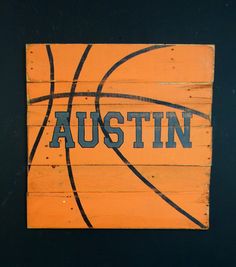 an orange wooden sign with the word austin written on it and a basketball inside