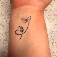 a woman's wrist with a butterfly and heart tattoo on the left side of her arm