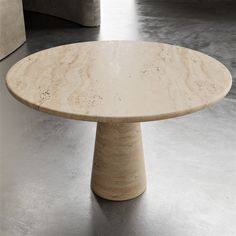 a round marble table sitting on top of a metal floor covered in white walls and concrete floors