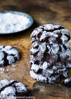 chocolate crinkle cookies with powdered sugar on top and two plates in the background