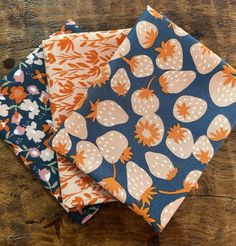 four different patterns of fabric on a wooden surface, each with an orange and blue design