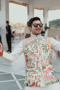 a man with sunglasses on his face is standing in front of an open room and holding out his hands