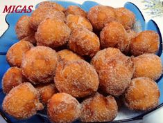 a blue bowl filled with sugar covered donuts