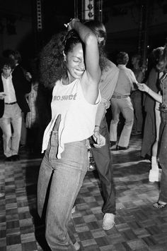 a woman dancing on the dance floor with other people in the background at an event