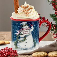 a frosted mug with a snowman on it and cookies next to the mug