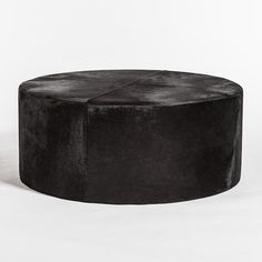 a black round ottoman sitting on top of a white floor