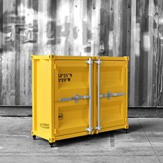 a yellow container sitting in front of a metal wall