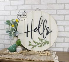 a wooden sign with the word hello painted on it next to flowers and vases