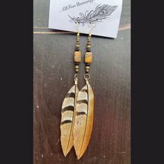 a pair of earrings with feathers hanging from it