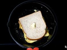 an egg and cheese sandwich in a skillet on a black surface with the words, how to make scrambled eggs