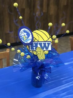 a blue table cloth topped with a plastic vase filled with water and basketballs on it