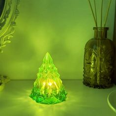 a green lighted christmas tree sitting on top of a white counter next to a mirror