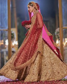 a woman in a red and gold bridal gown is walking down the aisle with her bouquet