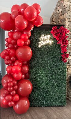 red balloons and greenery in front of a happy birthday sign with roses on it