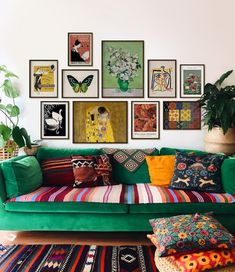 a green couch sitting in front of a wall filled with pictures and pillows on top of it