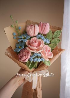 a hand holding a bouquet of flowers made out of crocheted wool and yarn