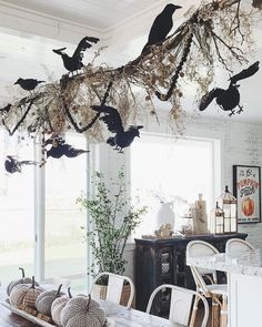 the dining room table is decorated with pumpkins and birds hanging from it's branches