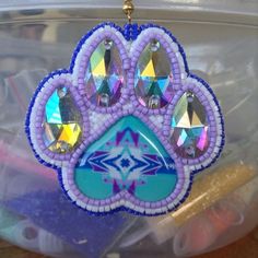 a purple dog paw shaped ornament hanging from a gold - plated chain