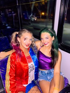 two women dressed in costumes sitting next to each other on a train car at night