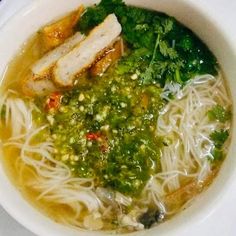 a white bowl filled with noodles, meat and veggies