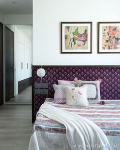 a bedroom with two pictures on the wall above the bed and pillows in front of it