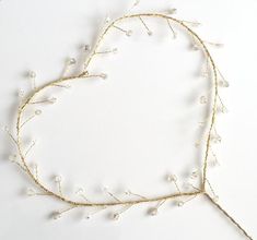 a heart shaped frame made out of branches and pearls