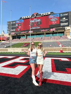 two women standing in front of a football stadium