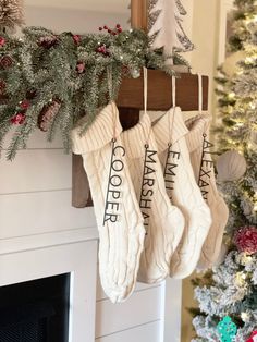 christmas stockings hanging from a mantel in front of a fireplace with evergreens and pine cones