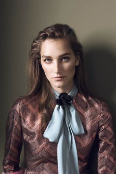 a woman with long hair wearing a dress and a blue bow tie is posing for the camera