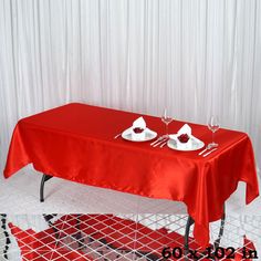 a red table cloth with two white plates on it and silverware sitting on top