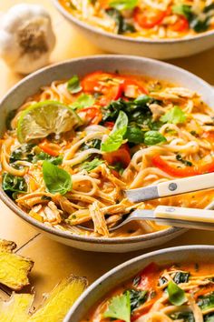 two bowls filled with noodles and vegetables on top of a table