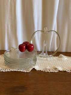 two cherries sitting on top of a glass cake plate next to a lace doily