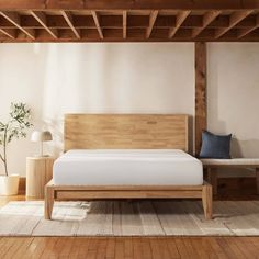 a bed with wooden frame and headboard sitting on a rug next to a lamp