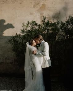 a bride and groom standing in front of a wall with shadows on the ground behind them